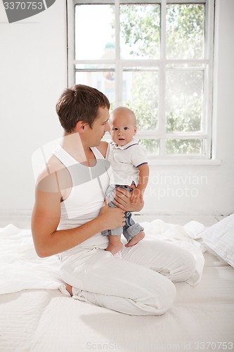 Image of young father with his nine months old son on the bed at home