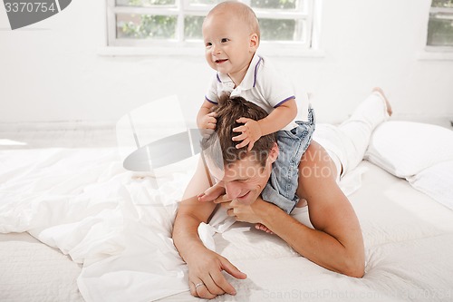 Image of young father with his nine months old son on the bed at home