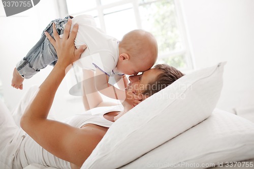 Image of young father with his nine months old son on the bed at home