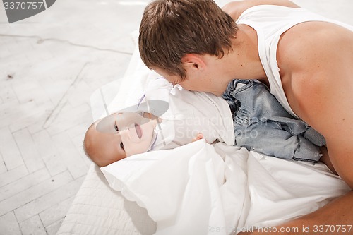 Image of young father with his nine months old son on the bed at home