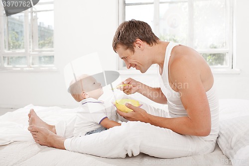 Image of Young father with his nine months old son on the bed at home