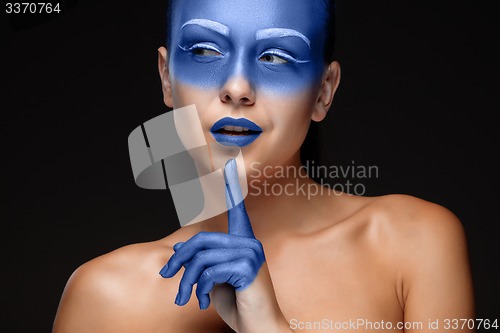 Image of Portrait of a woman who is posing covered with blue paint