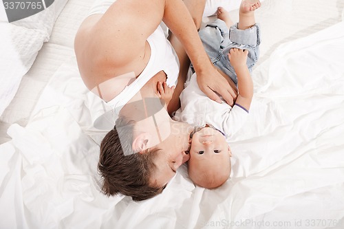 Image of young father with his nine months old son on the bed at home