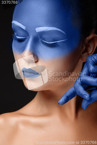 Image of Portrait of a woman who is posing covered with blue paint