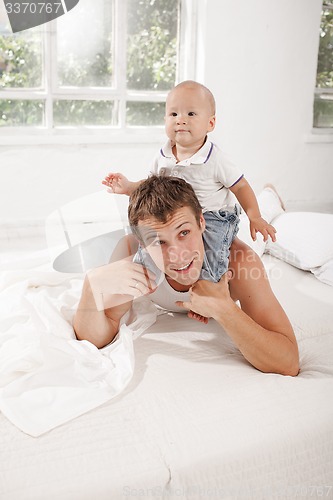 Image of young father with his nine months old son on the bed at home