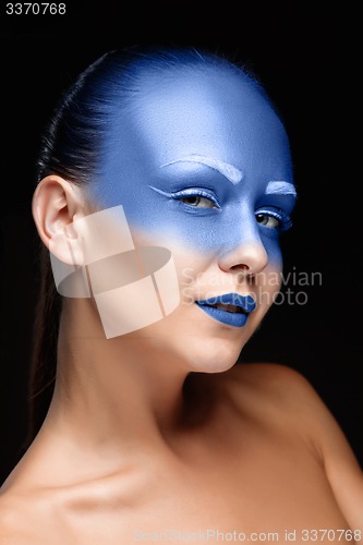 Image of Portrait of a woman who is posing covered with blue paint