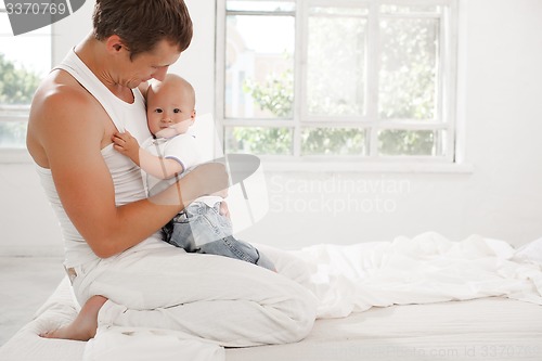 Image of young father with his nine months old son on the bed at home