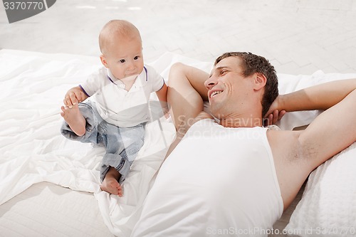 Image of young father with his nine months old son on the bed at home