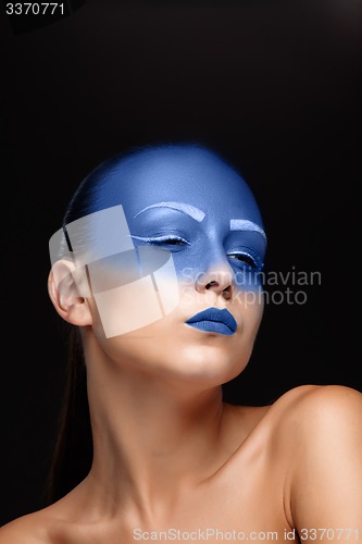 Image of Portrait of a woman who is posing covered with blue paint