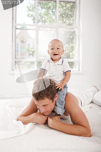 Image of young father with his nine months old son on the bed at home