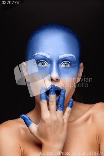 Image of Portrait of a woman who is posing covered with blue paint