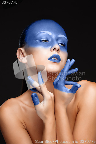 Image of Portrait of a woman who is posing covered with blue paint