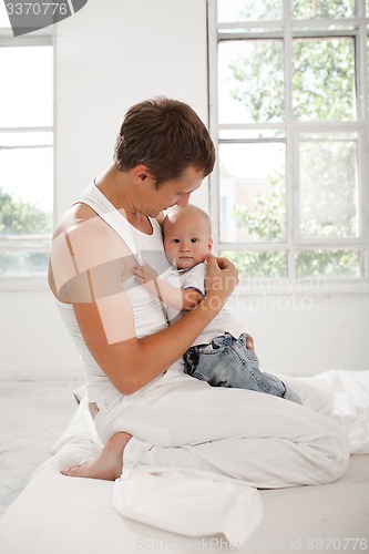 Image of young father with his nine months old son on the bed at home