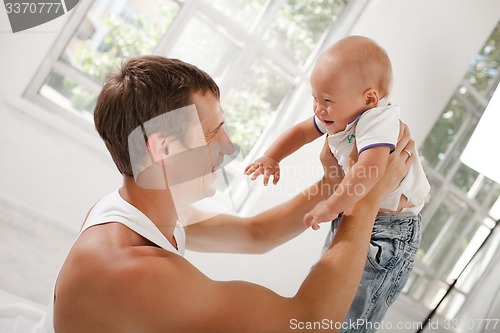 Image of young father with his nine months old son on the bed at home