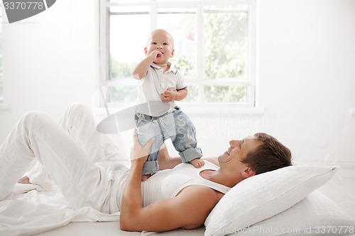 Image of young father with his nine months old son on the bed at home