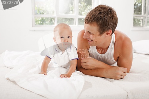 Image of young father with his nine months old son on the bed at home