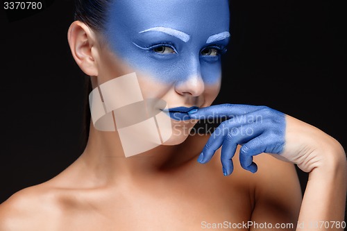 Image of Portrait of a woman who is posing covered with blue paint