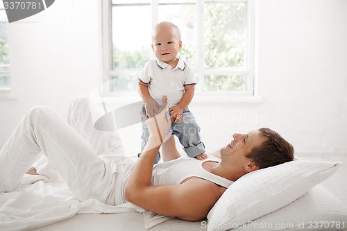 Image of young father with his nine months old son on the bed at home