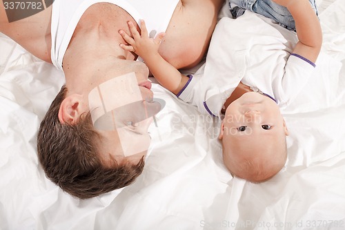 Image of young father with his nine months old son on the bed at home