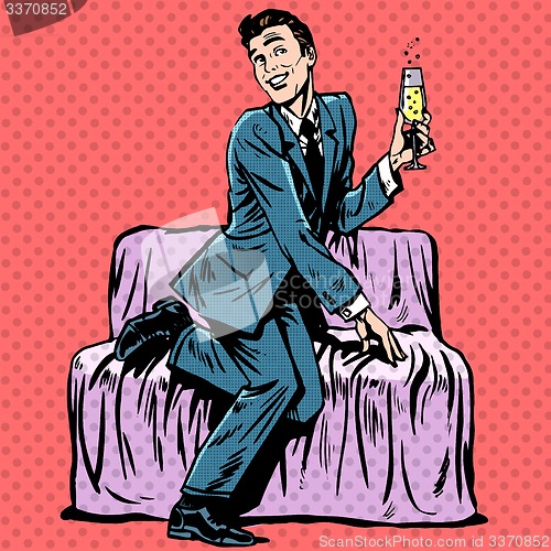 Image of Playful man with a glass of champagne on the couch