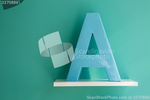 Image of Letter A turquoise color on a white shelf.