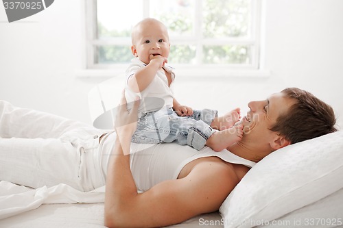 Image of young father with his nine months old son on the bed at home