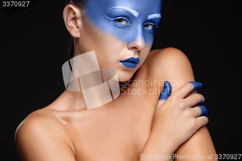 Image of Portrait of a woman who is posing covered with blue paint