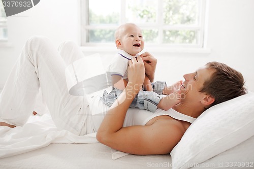 Image of young father with his nine months old son on the bed at home