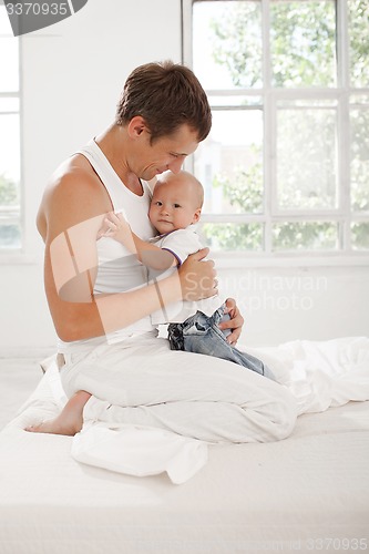 Image of young father with his nine months old son on the bed at home