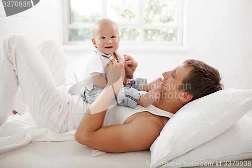 Image of young father with his nine months old son on the bed at home