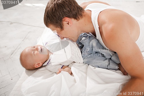 Image of young father with his nine months old son on the bed at home