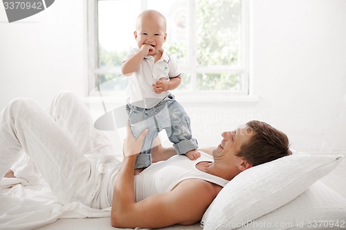 Image of young father with his nine months old son on the bed at home