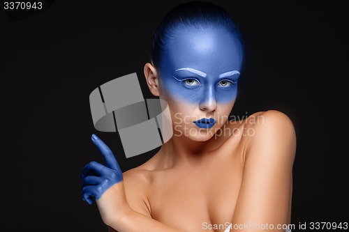 Image of Portrait of a woman who is posing covered with blue paint