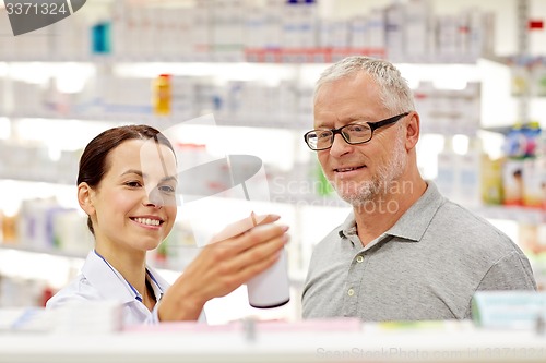 Image of pharmacist showing drug to senior man at pharmacy