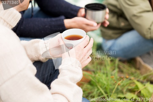 Image of close up of hikers drinking tea from cups at camp