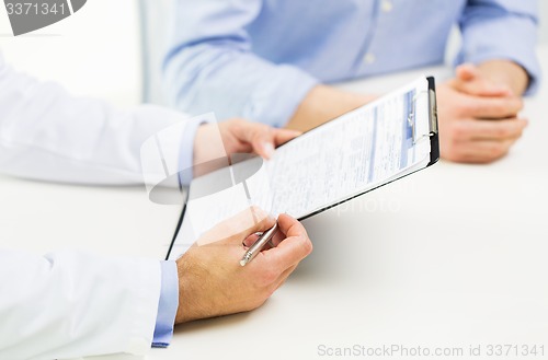 Image of close up of male doctor and patient with clipboard