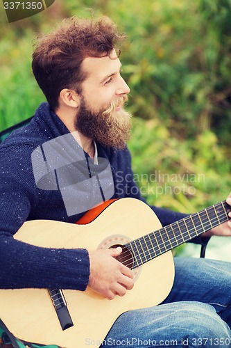 Image of smiling man playing guitar in camping