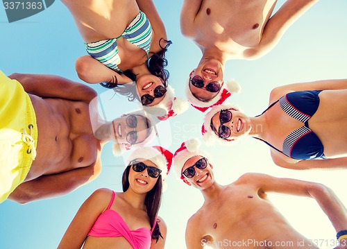 Image of smiling friends in circle on summer beach