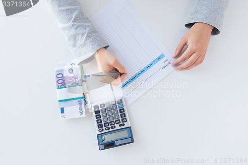 Image of close up of hands counting money with calculator
