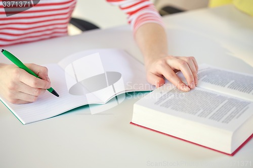 Image of close up of female hands with book and notebook