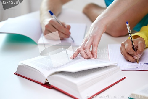 Image of close up of students hands writing to notebooks