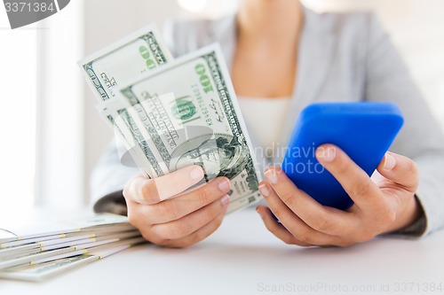 Image of close up of woman hands with smartphone and money