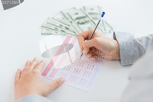 Image of close up of hands with lottery ticket and money