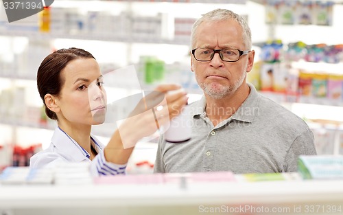 Image of pharmacist showing drug to senior man at pharmacy