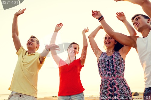 Image of smiling friends dancing on summer beach