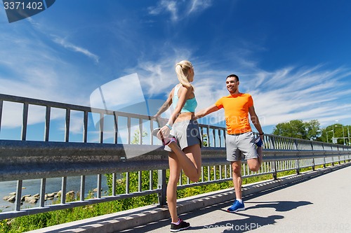 Image of smiling couple stretching outdoors