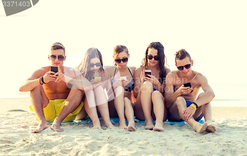 Image of friends with smartphones on beach