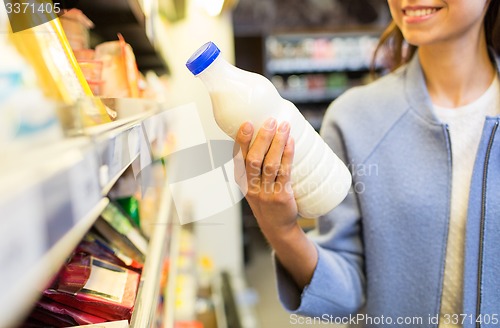 Image of happy woman holding milk bottle in market