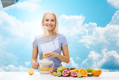 Image of smiling woman squeezing fruit juice over sky