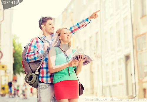 Image of smiling couple with city guide and backpack